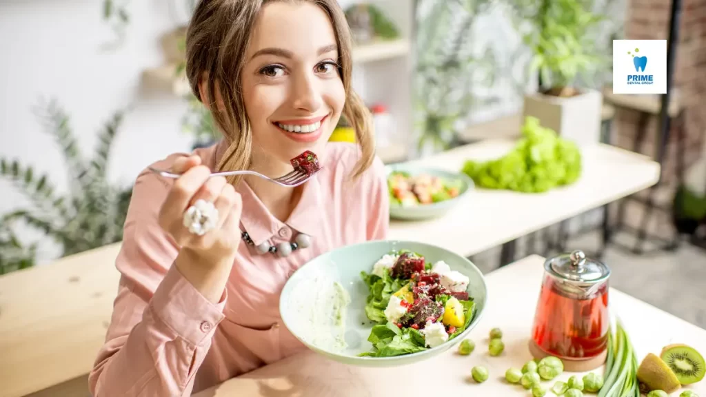 Smiling woman eating a healthy salad, promoting a teeth-friendly diet for better oral health.