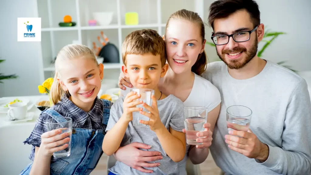 A happy family drinking water together, promoting hydration for healthy saliva production and oral health.