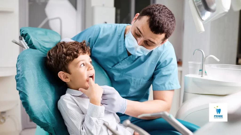 A dentist in scrubs helps a young boy point to his teeth during dental check ups.