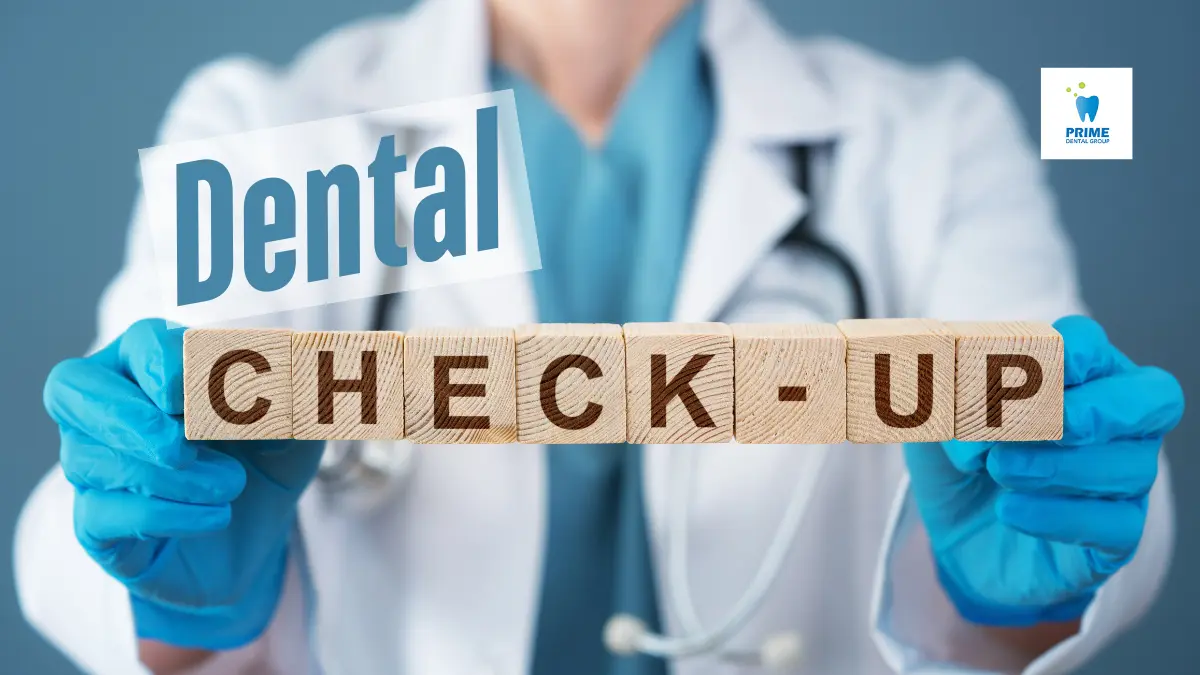 Dentist holding wooden blocks spelling "Dental Check Ups" with a Prime Dental Group logo in the background.