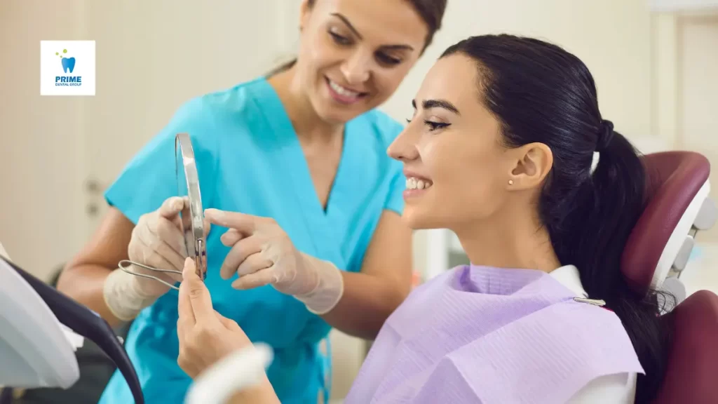 A happy woman at the dentist’s office looking at her smile in a mirror after a professional cleaning.