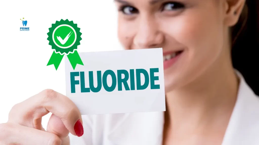 A smiling woman holds a card with the word "Fluoride" and a green safety certification badge, emphasizing fluoride’s safety and benefits.