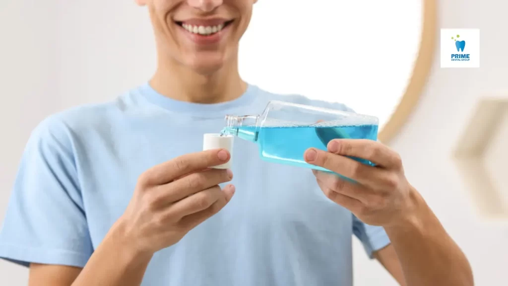 A smiling man pours fluoride mouthwash into a cap, preparing to use it for fresh breath and cavity protection.